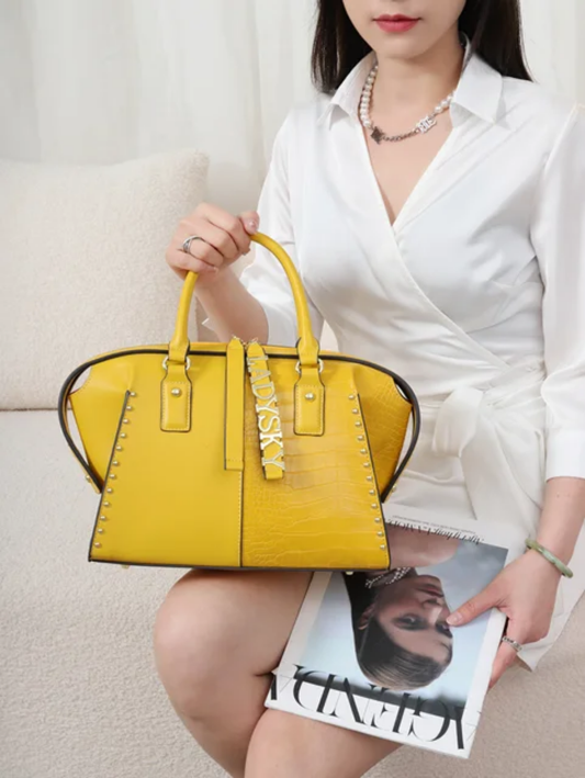 The Art of Handbags -A woman sitting on a chair holding a Luxury Yellow Handbag on the lap.
